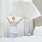 39433941 – happy female chambermaid making bed in hotel room
